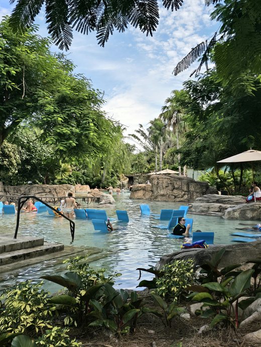 Guests floating on blue chairs along a tropical lazy river.