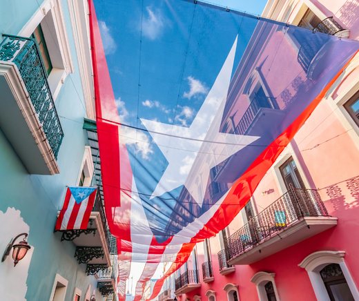 A large Puerto Rican flag hung across a colorful Old San Juan street.