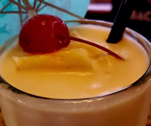 A creamy piña colada topped with pineapple and a cherry.