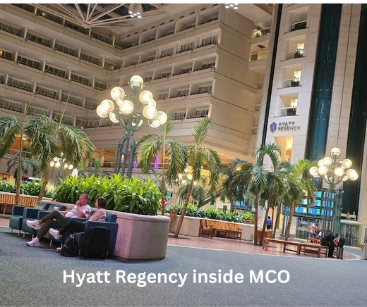 The Hyatt Regency atrium inside Orlando International Airport, with palms and the hotel sign.